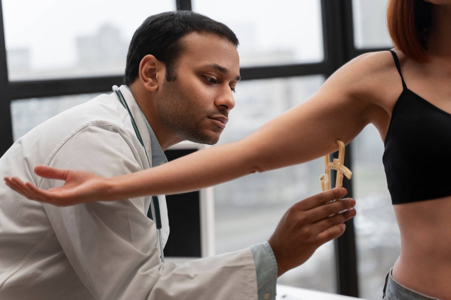 Clinician measuring a patient's upper arm with a skinfold caliper