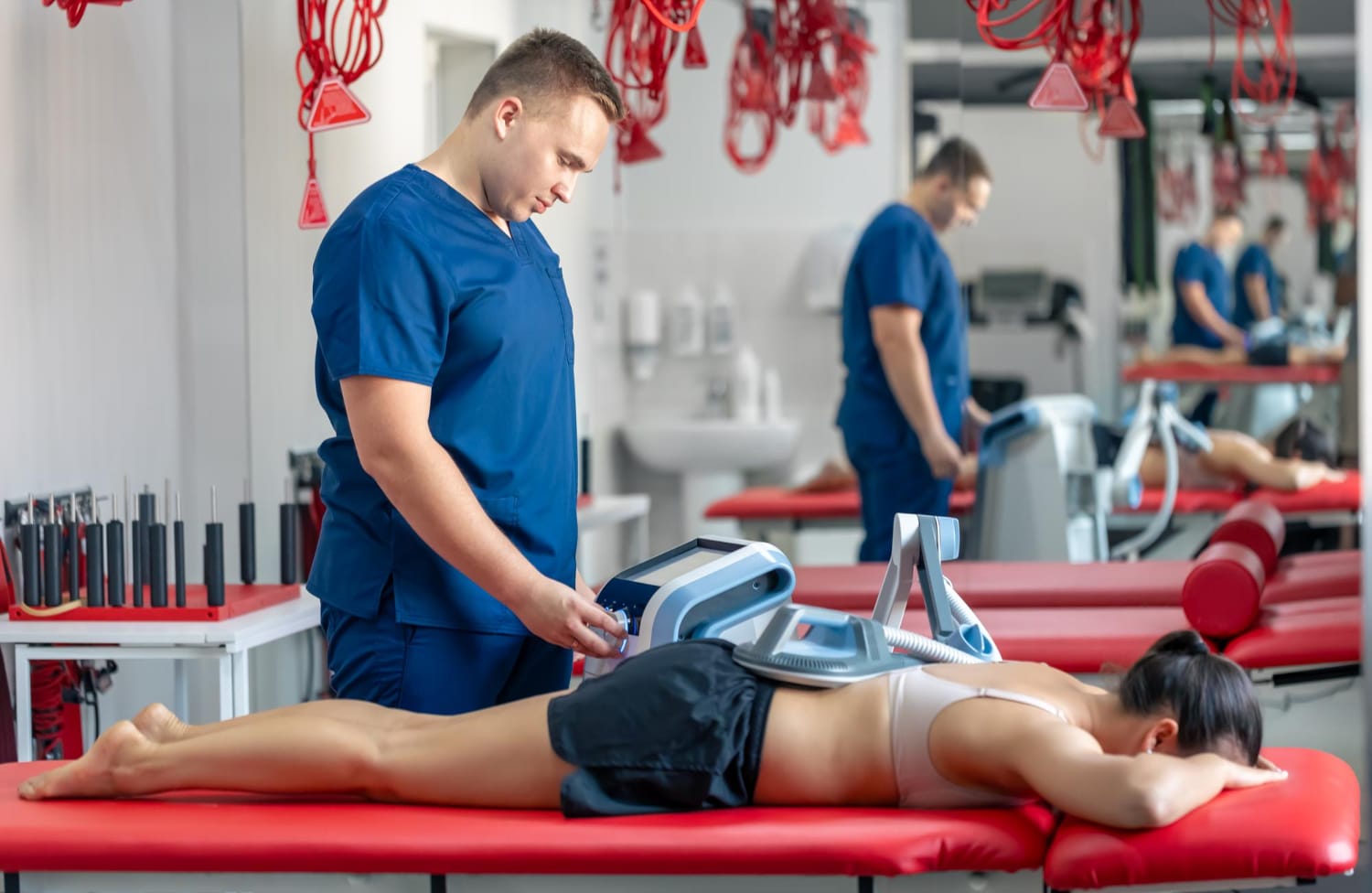 Therapist adjusting a therapy device placed on a patient's lower back