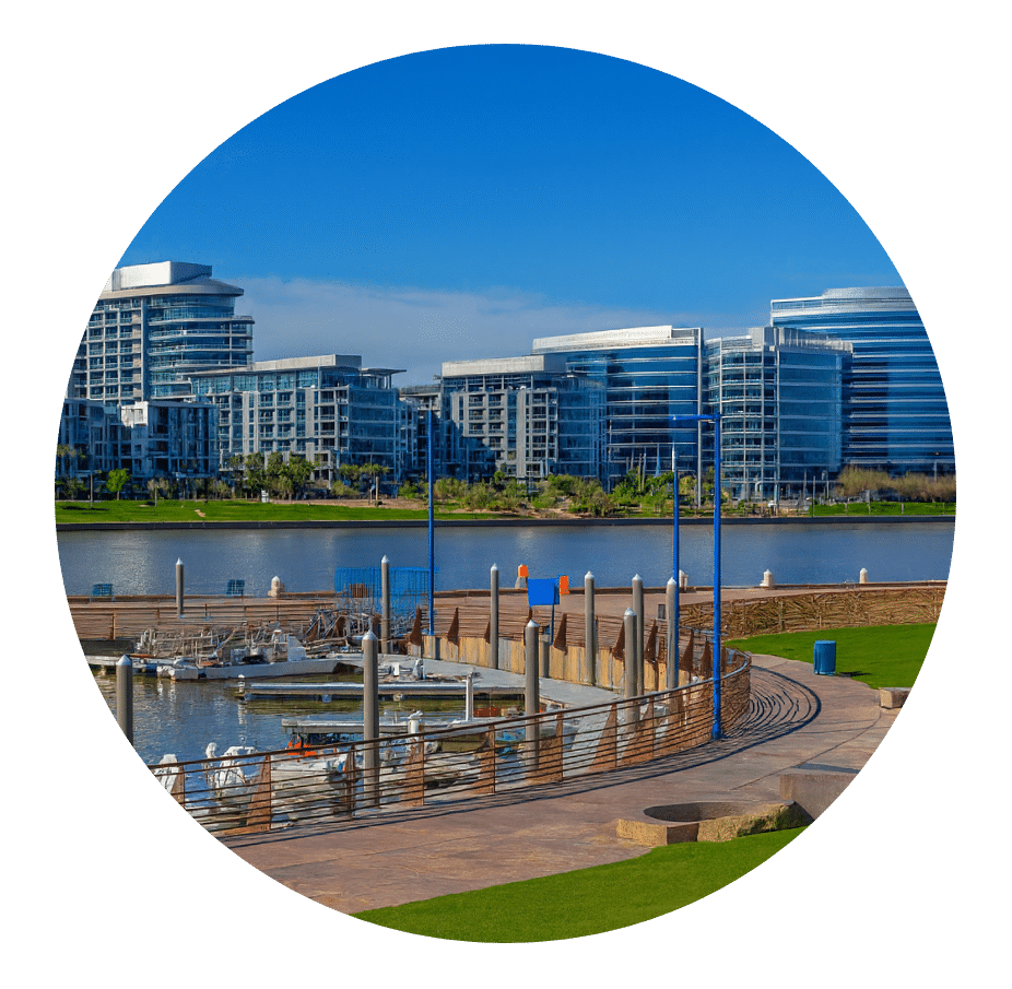 Glass high-rises across a lake beside a marina walkway
