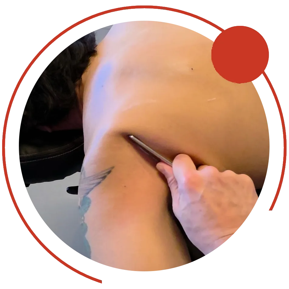 Instrument-assisted soft tissue work on a client's shoulder